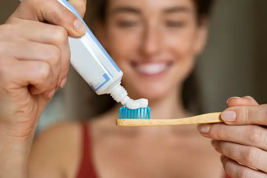 A woman using toothpaste to treat her dry mouth sensation as an alternative to using the best dry mouth products Best dry mouth products