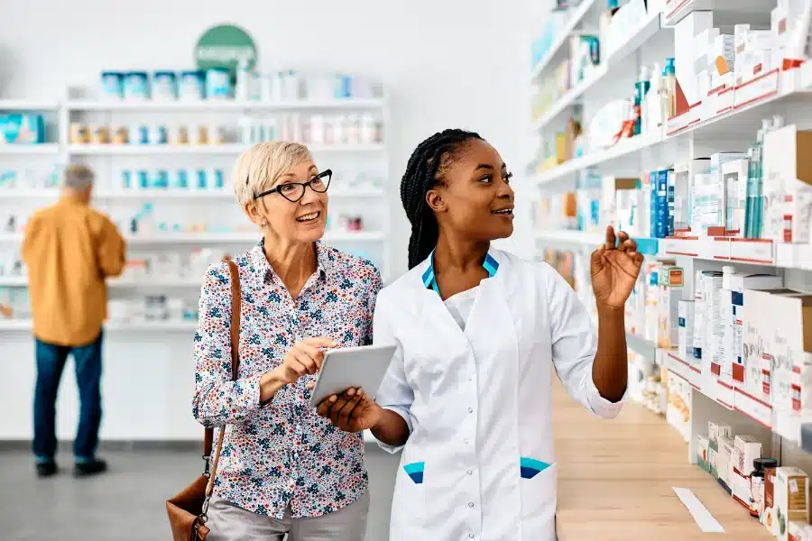 An elderly woman and a female pharmacist looking at the products on a shelf display to relieve her Dry Mouth A Symptom of Covid