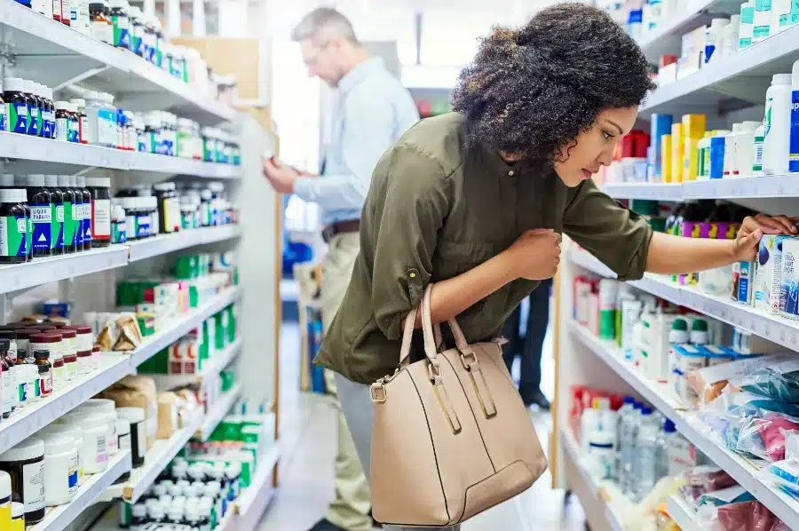 A woman in a shopping aisle looking at ingredients to determine which are the best dry mouth products