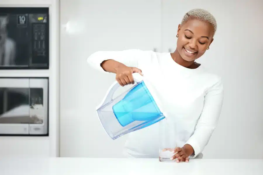 A woman pouring a glass of water because she has cotton mouth from edibles