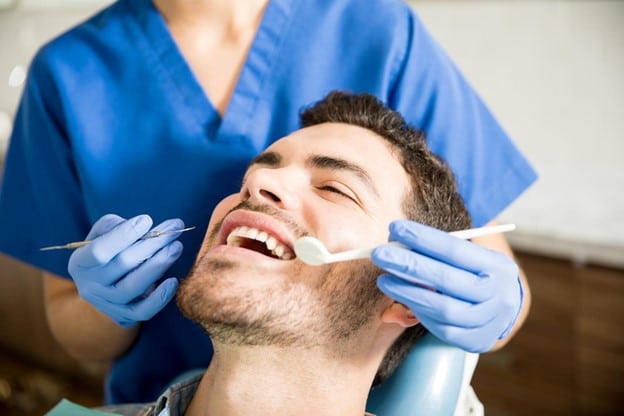 A man being seen by a dentist for one of the regular checkups he schedules to keep on top of the impact his diabetes and dry mouth have on his oral health