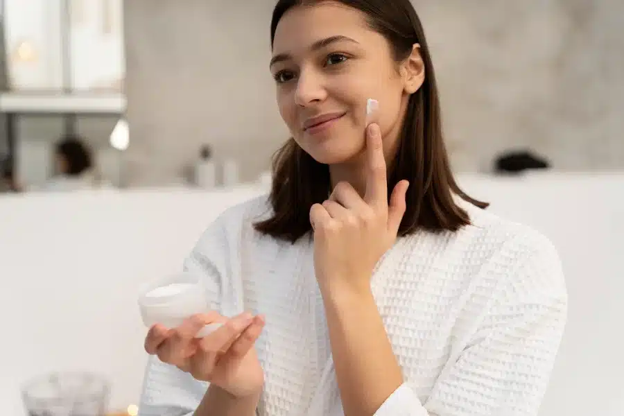 A woman applying a facial moisturizer formulated with Hyaluronic Acid.