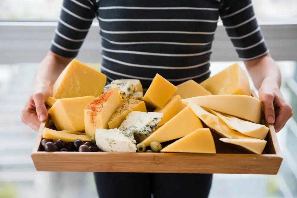 A person with a tray of cheese as cheese is one food that could be beneficial for How To Strengthen Your Teeth.