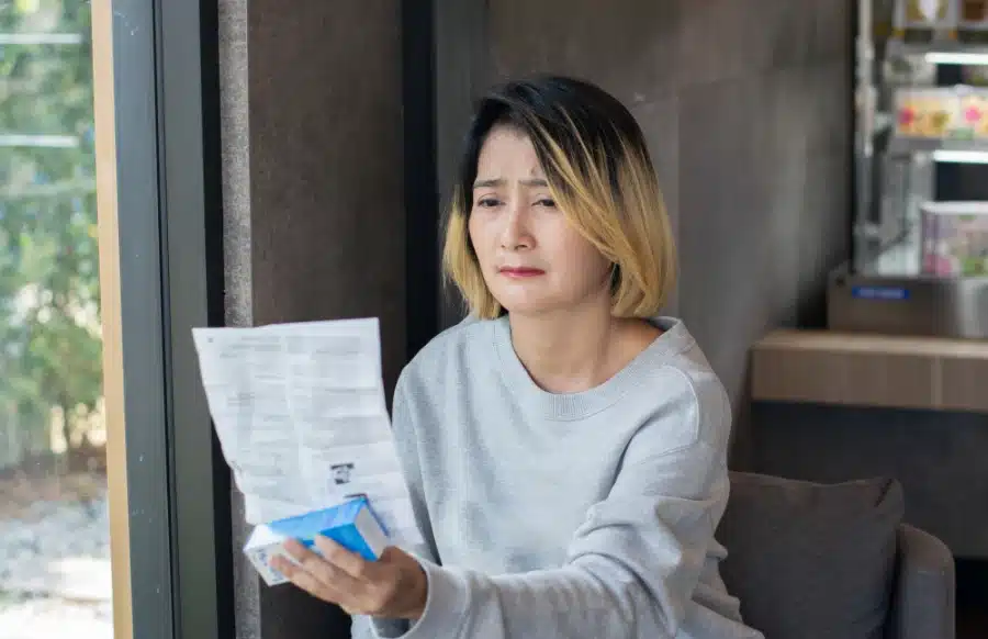 Alt Text: A woman examining the ingredient list of a product she recently purchased to see if it is paraben free.