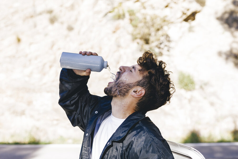 A man drinking water wondering Why Do You Get Cotton Mouth When You’re High. 