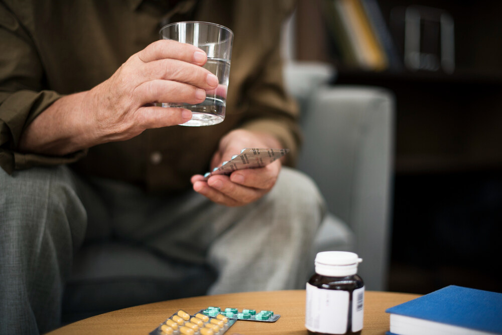 A man taking medications while thinking about possible dry mouth remedies he can use to get rid of the pesky dry mouth side effects he’s experiencing from his meds.