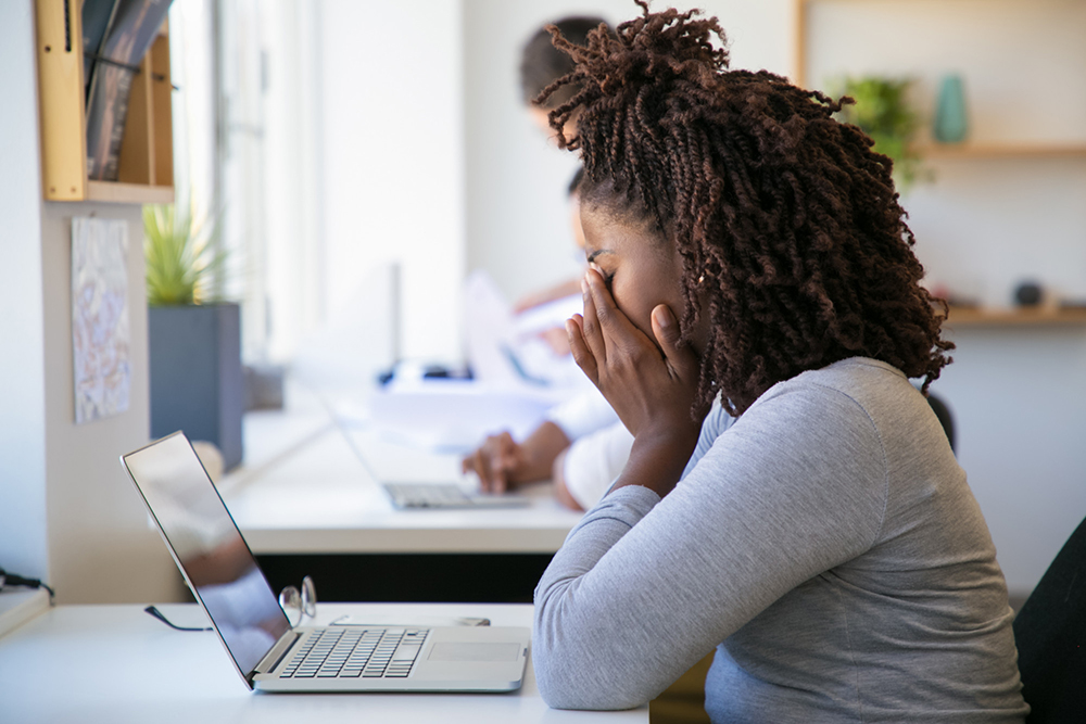  A lady sitting at her computer exhausted from grappling with her stress and dry mouth.
