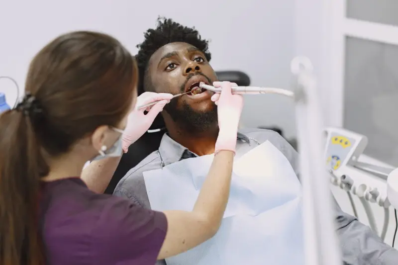 A man at the dentist receiving a below the gum line cleaning to help prevent him from developing Periodontal Disease.