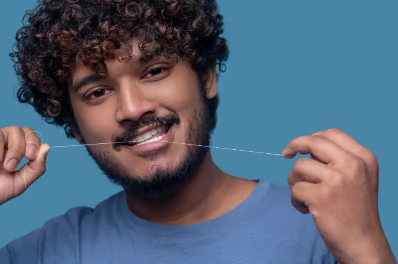 A man flossing and practicing proper oral hygiene to prevent getting Periodontal Disease.