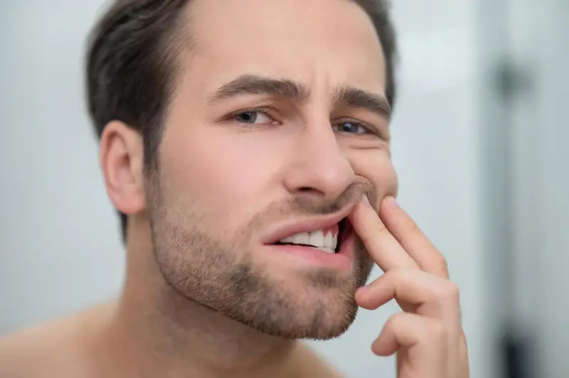 A man checking his teeth to see if he has any early warning signs of Periodontal Disease