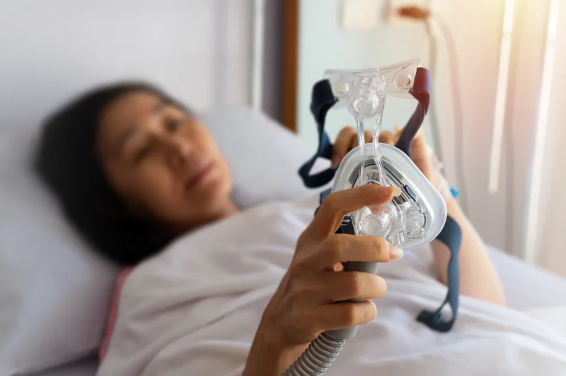 A woman with CPAP dry mouth adjusting her mask.