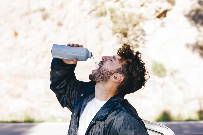 A man suffering from CPAP dry mouth drinking water to try relieving it.